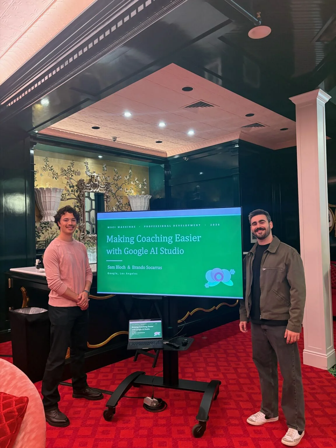 Sam Bloch and Brando Socarras beside a screen reading 'Making Coaching Easier with Google AI Studio' at the Grand Hotel